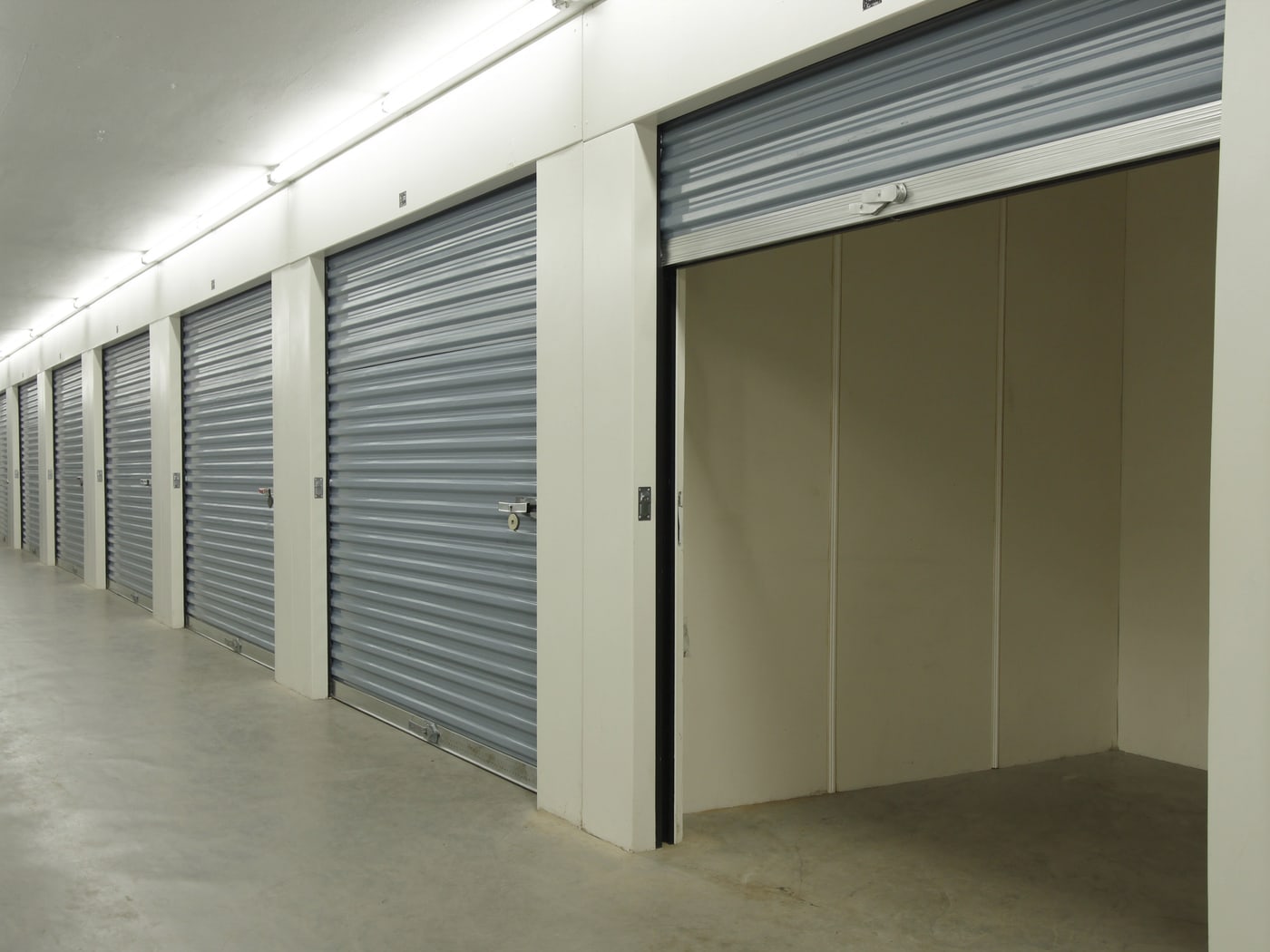 Rangée d'unités de stockage modulaires à portes rideaux en acier, une unité ouverte et vide
